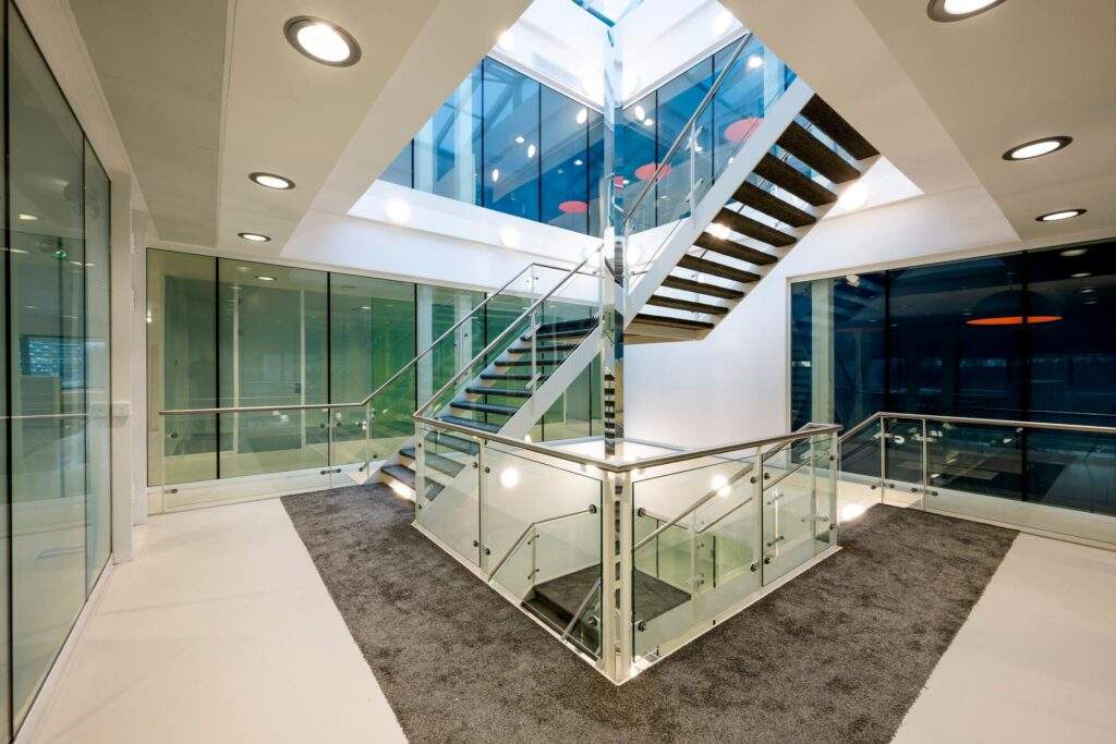 Moderne, glazen trappenhuis in een kantoorgebouw aan de Prof. E.M. Meijerslaan met strakke lijnen en veel natuurlijk licht.